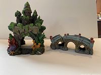 Photo of two aquarium resin decorations: a castle and a stone bridge, showing full view and details