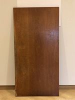 Top side of wooden desktop table top showing dark brown finish with signs of wear and chipping.