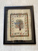 Frontal view of framed Egyptian hieroglyphs papyrus print chart with German alphabet and tree illustration.