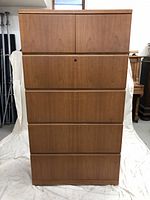 Full front view of closed lateral file cabinet showing 2 top doors and 4 drawers, clad in cherry wood finish.