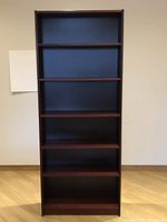 Front view of maroon IKEA Billy bookcase showing shelves.