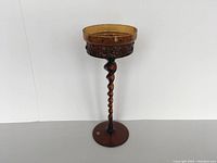 Front view of the amber votive candle holder showing twisted stem and broad circular base.