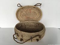 Top-down view of the open woven basket showing the interior and lid attached by rope handles.