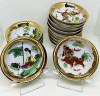 Image showing two stacks of small scalloped edge porcelain bowls with hand painted dragon motifs and seated figure designs, all with gold rims.