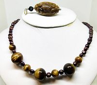 Full view of the 18 inch vintage beaded necklace displaying polished Tigers Eye beads and dyed freshwater pearl beads on a white stand