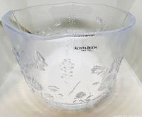 Front side showing clear glass bowl with embossed floral and butterfly patterns and original Kosta Boda sticker