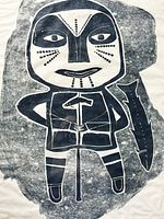 Close-up of the black and white Inuit figure with traditional markings, holding a spear with a fish beside it.