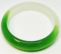 Top-down photo of circular jade bangle bracelet showing vibrant green to white color gradient and polished surface.