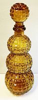 Full view of amber glass decanter with stopper in place on white background