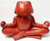 Front view of the red frog sculpture showing its stance and facial details, highlighting some chips and wear.