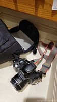 Canon SX-40 HS digital camera next to Lowepro bag with camera strap visible