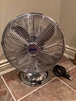 Full front side view of the heavy metal desk fan on tiled floor.