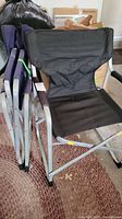 Two black canvas folding chairs, one open and one folded, showing silver metal frame and armrests.