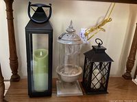 Photo showing all three lanterns on a wooden surface under a table with a power outlet behind.