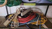 Photo showing two beige power strips with multiple outlets lying on top of a pile of extension cords in red, yellow, blue, black, and beige colors.