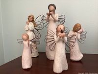 Five Willow Tree angel figurines arranged on a shelf showing the entire set and their wire wings.