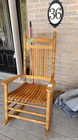 Front view of full wooden slatted rocking chair on porch