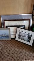 Four framed boat-related pictures and drawings arranged on floor showing frames and images.