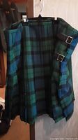 Men's XXL tartan kilt hanging on a hanger showing blue, green, and black check pattern.