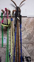 Two Fischer downhill skis, wood cross country ski, and poles hanging on coat hooks