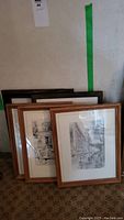 Stack of six framed black and white Vancouver drawings leaning against wall