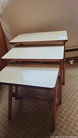 Set of three nesting tables stacked with laminate tops and wooden legs