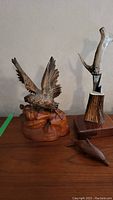 Full view of wooden eagle carving, wooden dolphin figurine, and stag handle knife in wood block on surface