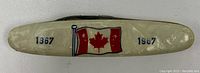 Close-up photo of folding knife handle with Canadian flag and dates 1867 1967.