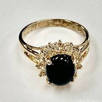 Front-facing detailed shot of ring showing black onyx center stone surrounded by clear gemstones