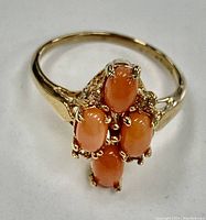 Close-up photo of the ring showing the coral gemstone cluster from an angle, highlighting the gold electroplated band and the gemstones' pink-orange color.