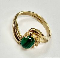 Close-up photo of the gold plated ring with green malachite gemstone showing front angle and details of setting and band.