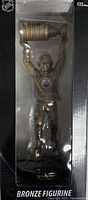 Photo of Wayne Gretzky bronze figurine in packaging, holding Stanley Cup trophy overhead, visible Edmonton Oilers logo on jersey.