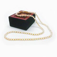Full view of the white jade bead necklace with gold-colored accents displayed on a decorative black and red box with Asian design.