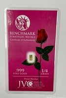 Front of certificate card showing Benchmark Strategic Metals logo, .999 fine gold label, 1/4 grain weight, and embedded gold piece with rose illustration.