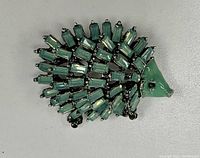 Front view of the brooch showing green enamel face and rhinestone crystal body detail.