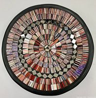 Top view showing circular glass inlay pattern with shades of red, purple, black, and white in mosaic style.