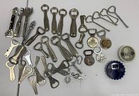 Top-down view of lot showing variety of vintage and assorted bottle openers in metal and plastic, with different styles and sizes.