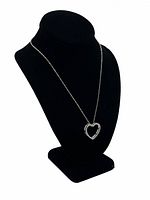 Silver heart necklace displayed on black velvet stand showing chain and pendant shape.