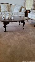 Full view of Broyhill wood grain coffee table on carpet in front of floral upholstered sofa set.