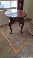 Full view of the Broyhill wood grain end table placed on carpet by window, showing overall shape and leg style.