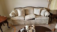 Full view of Broyhill floral pattern sofa with wooden trim, seat cushions, and multiple matching floral pillows.