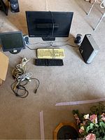 Photo taken containing entire desktop computer system with two monitors, two keyboards, speakers, tower, and assorted cords on carpeted floor.