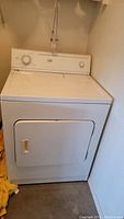 Front view of white Whirlpool Estate dryer showing door and control panel with dials.