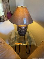 Glass-topped end table and decorative lamp with brown shade and carved wooden base