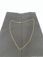 14k gold twisted link necklace approximately 19 inches long displayed on black fabric background.