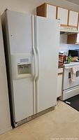 Full view of the white Kenmore side-by-side refrigerator, closed, showing water and ice dispenser on the left door.