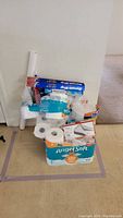 Image showing various paper products stacked including Angel Soft toilet paper, paper towels, envelopes, paper plates, napkins, and cups.