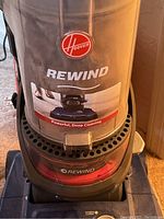 Close-up photo showing Hoover Rewind upright vacuum front with clear dirt canister and branding