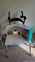 Photo of adjustable walker with seat and hand brakes; white padded seat with holes; black backrest and arm supports