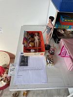 Overhead view of both Barbie dolls, box, stands and accessories on table